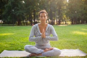 Woman sitting and meditating in a yoga mat which explains why 10 minutes meditation is importat